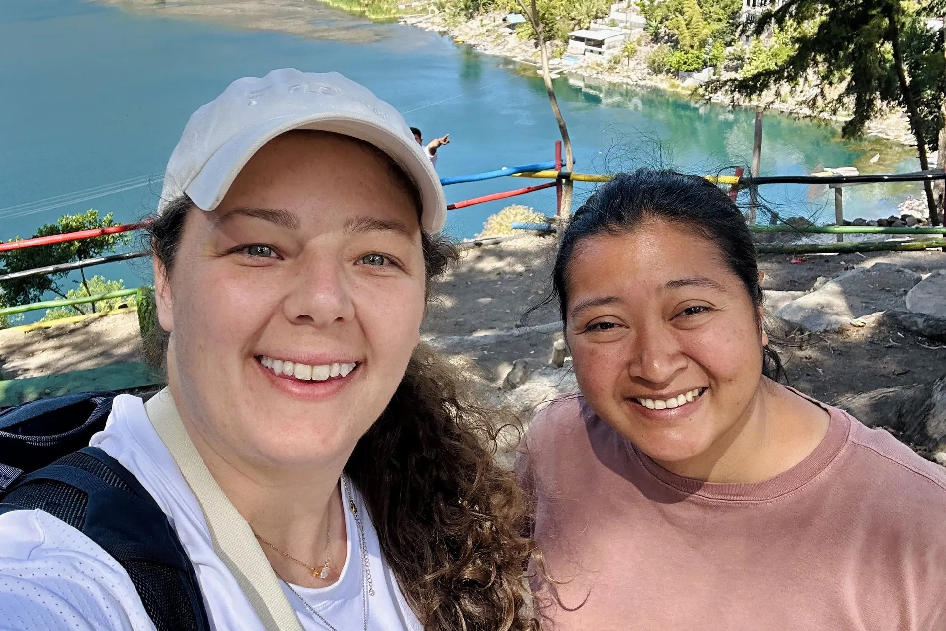 Jackie and Carly smiling at Xechivoy Viewpoint above Santiago Atitlán, with Lake Atitlán and the surrounding mountains behind them.